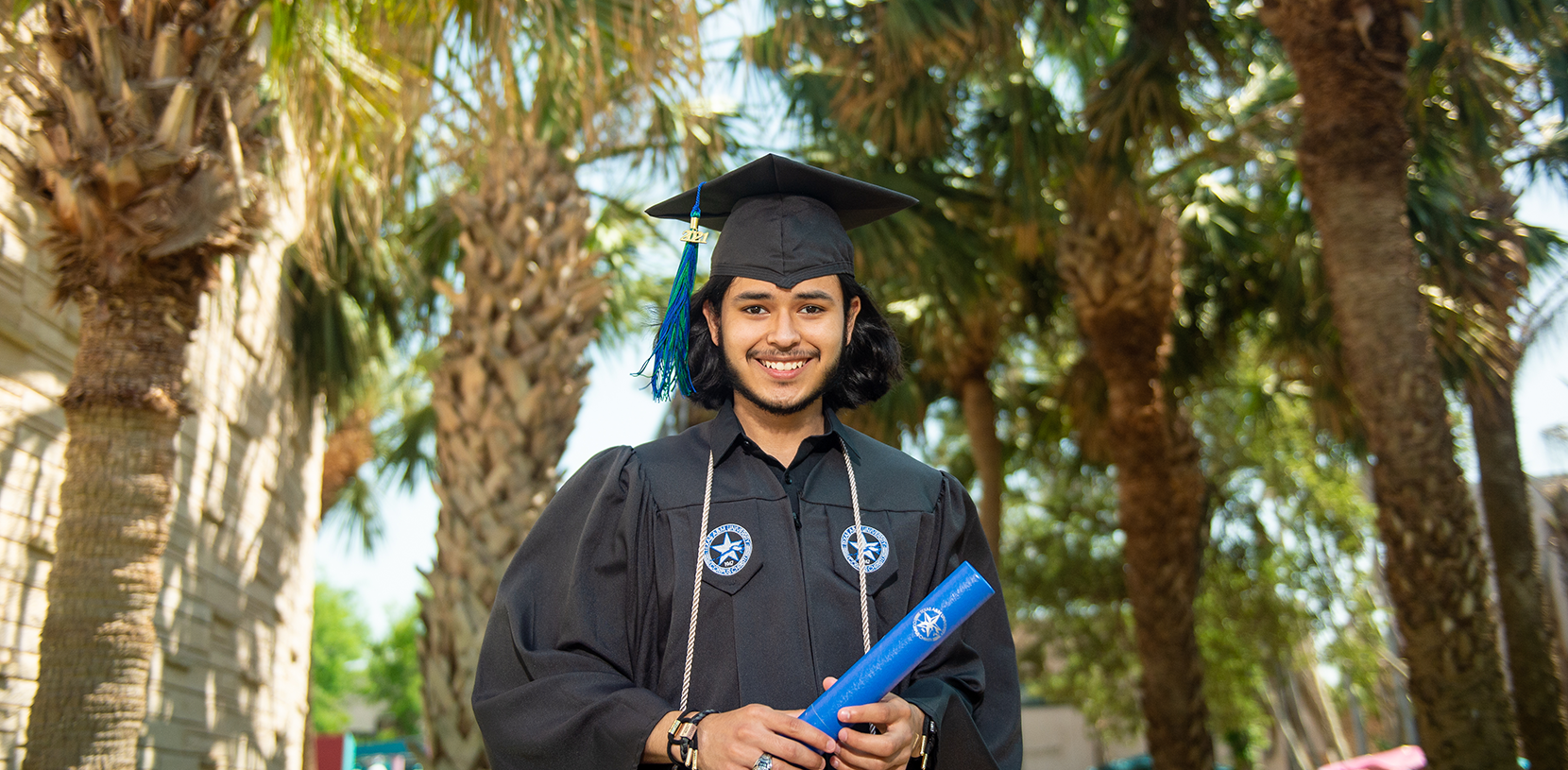 student, graduate in a cap and gown and holding a diploma