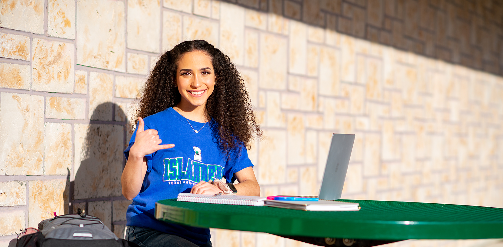 student Claudia Narvaez sitting with her lap top outside on campus