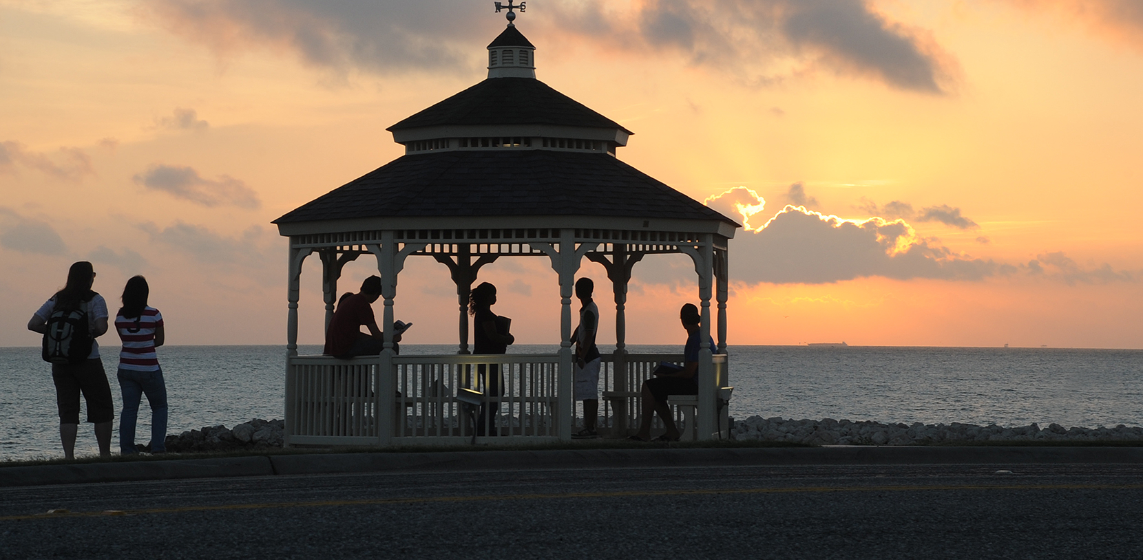 students in a gazebo by the sea at sunset