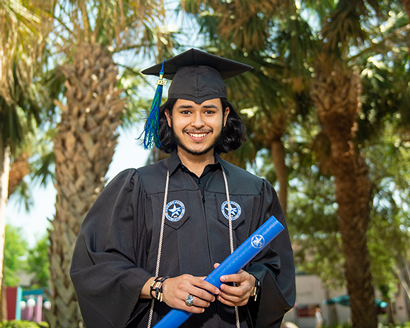 student, graduate in a cap and gown and holding a diploma